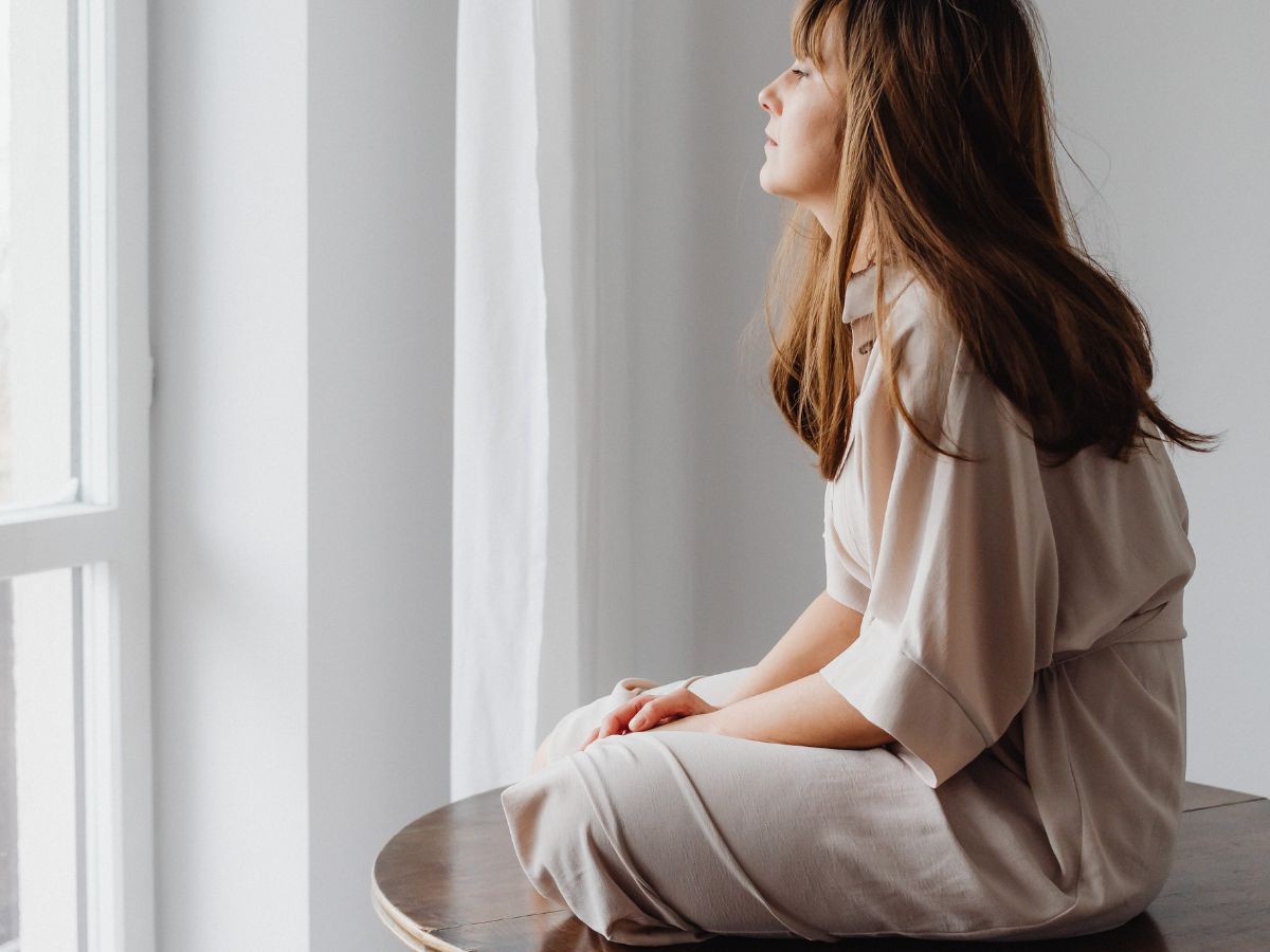 Woman reflecting by a window representing brain health, mood, anxiety, and trauma symptoms.